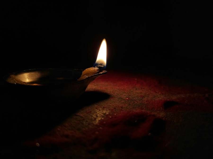 A single lit diya flame in the dark